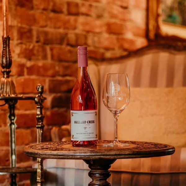 A bottle of Oakland Creek Vineyards Rosé on a vintage table in the tasting room