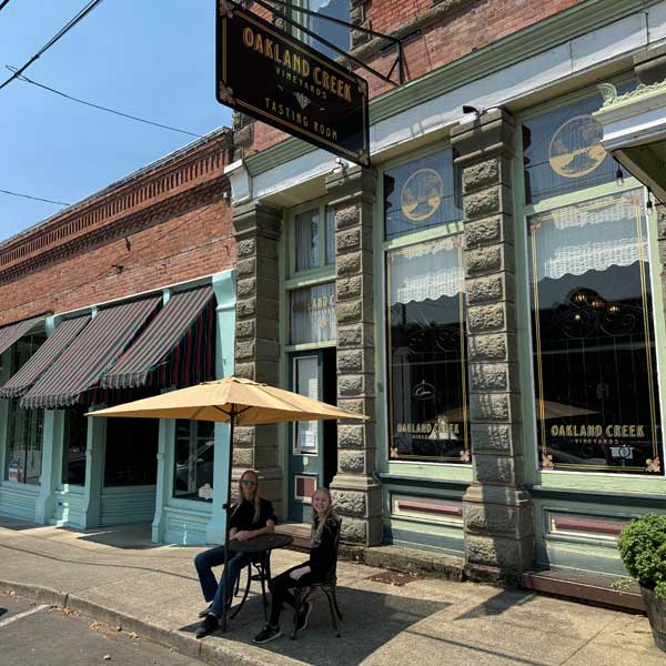 Two family members sitting outside of the Oakland Creek Vineyards tasting room.